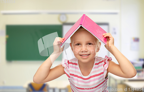 Image of little girl of book on top of her head at school