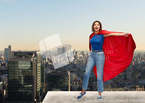 Image of happy woman in red superhero cape over tokyo city
