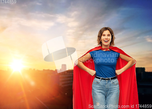 Image of happy woman in red superhero cape over city sunset