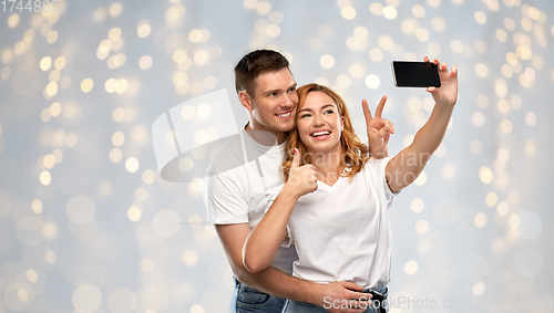 Image of happy couple in white t-shirts taking selfie