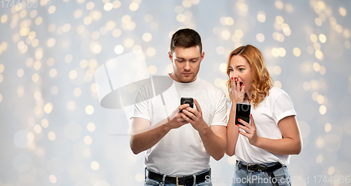 Image of happy couple in white t-shirts with smartphones