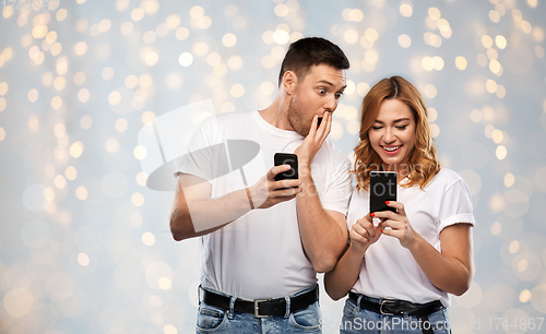 Image of happy couple in white t-shirts with smartphones