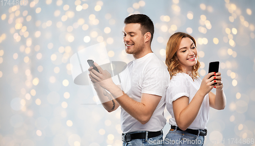 Image of happy couple in white t-shirts with smartphones