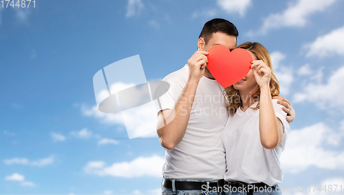 Image of smiling couple hiding behind big red heart