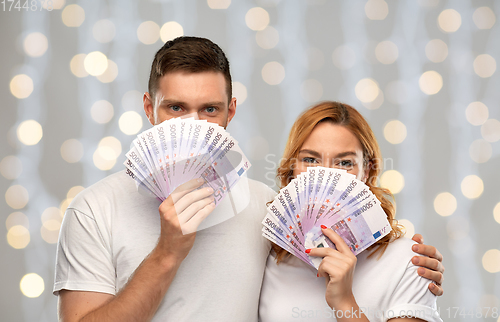 Image of happy couple in white t-shirts with euro money