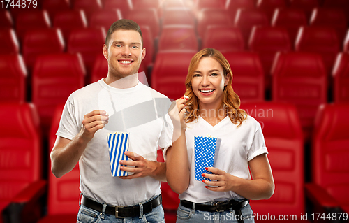 Image of happy couple eating popcorn at movie theatre