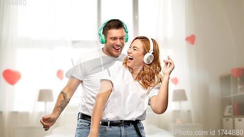 Image of happy couple in headphones dancing