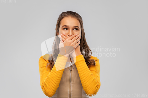 Image of scared teenage girl closing her mouth by hands