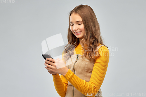 Image of smiling teenage girl using smartphone