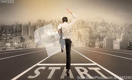 Image of Businessman jumping on a starting grid with cityscape on the background