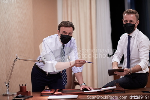 Image of business people wearing crona virus protection face mask on meeting
