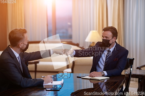 Image of business people wearing face mask on meeting and handshake