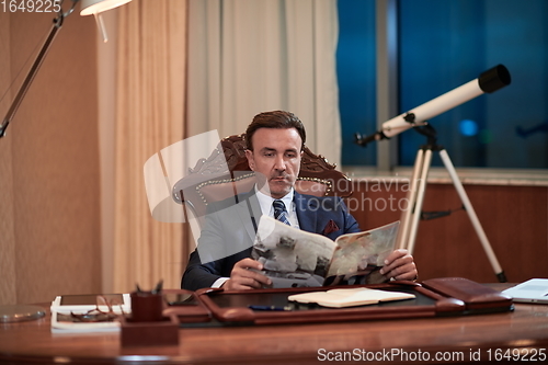 Image of corporate business man at office reading magazine