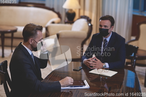 Image of business people wearing crona virus protection face mask on meeting