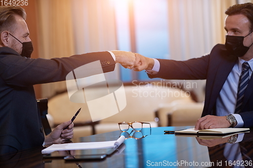 Image of business people wearing face mask on meeting and handshake
