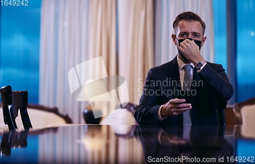 Image of business man using smart phone at luxury office wearing face mask