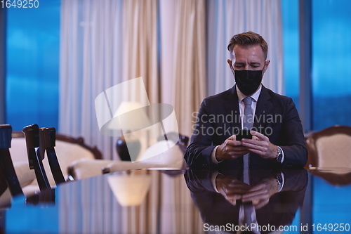 Image of business man using smart phone at luxury office wearing face mask