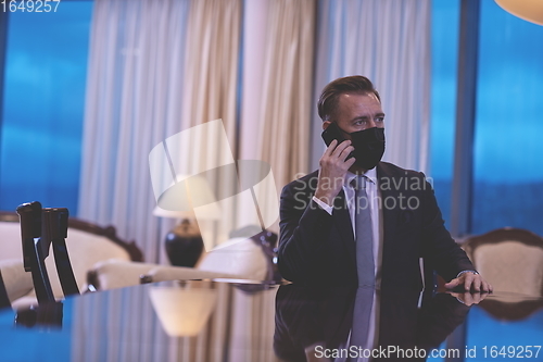 Image of business man using smart phone at luxury office wearing face mask