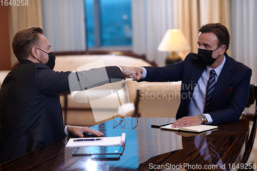 Image of business people wearing face mask on meeting and handshake