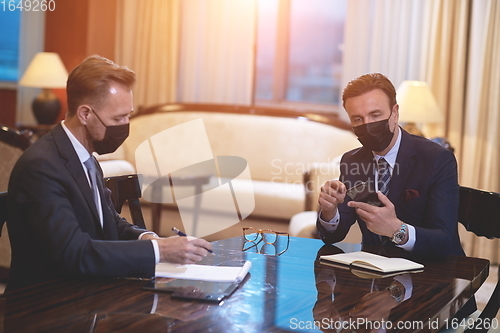 Image of business people wearing crona virus protection face mask on meeting