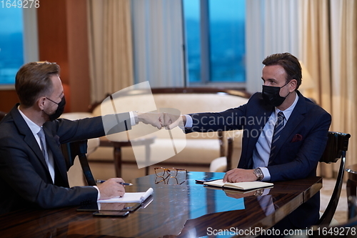 Image of business people wearing face mask on meeting and handshake
