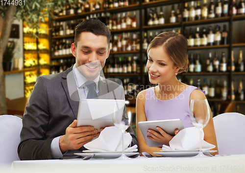 Image of couple with menus on tablet pc at restaurant