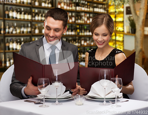 Image of smiling couple with menus at restaurant