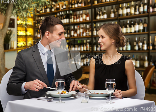 Image of smiling couple eating main course at restaurant