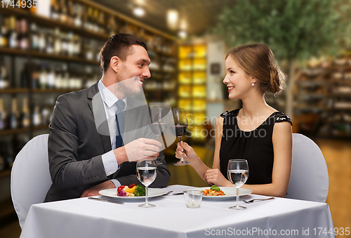 Image of smiling couple clinking wine glasses at restaurant