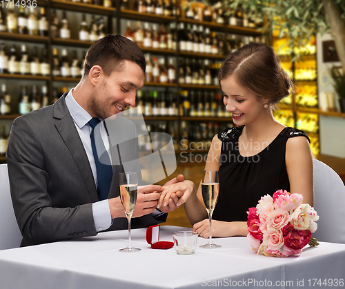 Image of man proposing to his girlfriend at restaurant