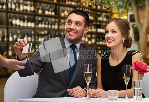 Image of hsppy couple paying with credit card at restaurant
