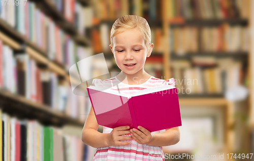 Image of smiling little girl reading book at library