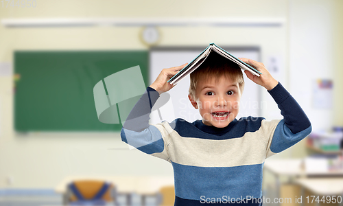 Image of little boy with book on top of his head at school