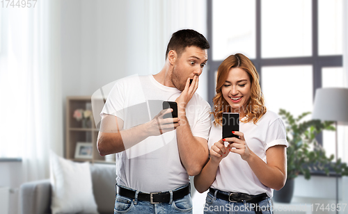 Image of happy couple in white t-shirts with smartphones