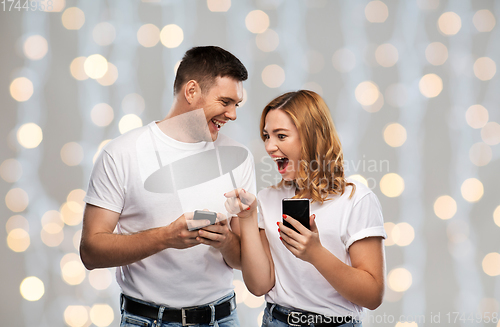 Image of happy couple in white t-shirts with smartphones
