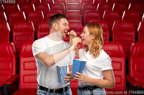 Image of happy couple eating popcorn at movie theatre