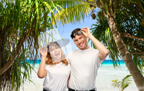 Image of happy couple in sunglasses on tropical beach