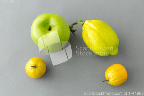 Image of close up of green apple and lemons on grey