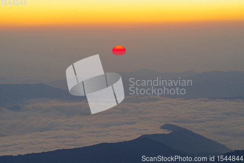 Image of Sunrise scene with red sun over the mountains