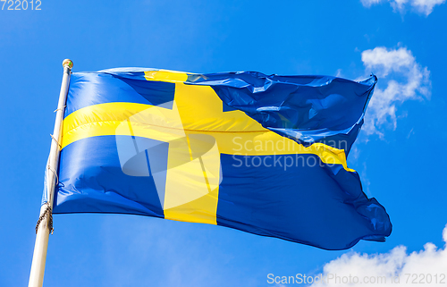 Image of Swedish flag blue with yellow cross waving in the wind against a