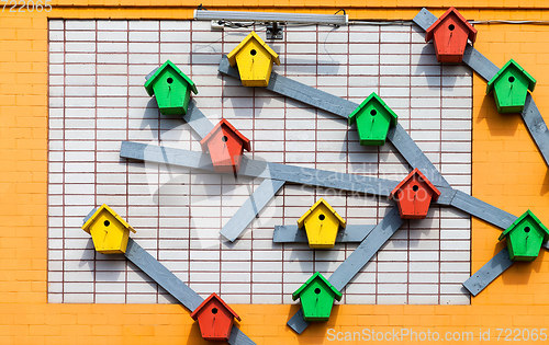 Image of Colourful wooden birdhouses mounted on the brick wall