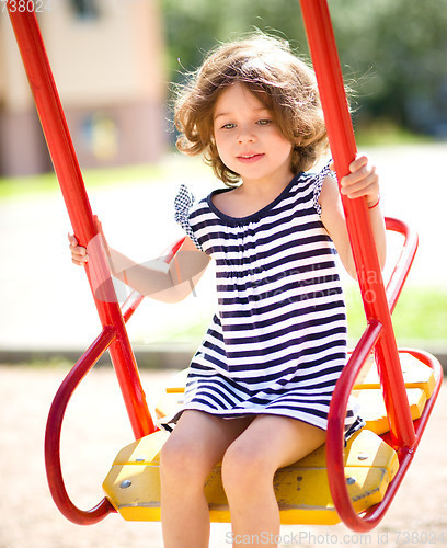 Image of Young happy girl is swinging in playground