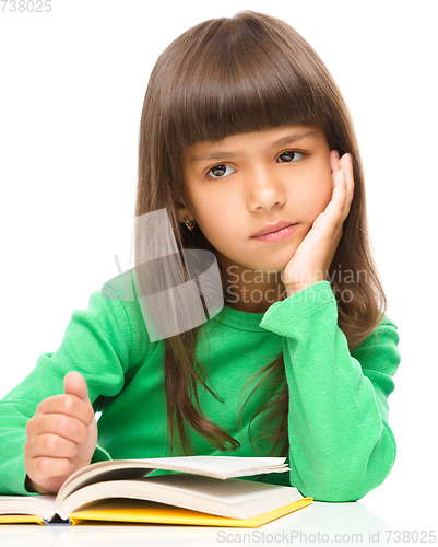 Image of Young girl is daydreaming while reading book