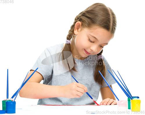 Image of Little girl is painting with gouache