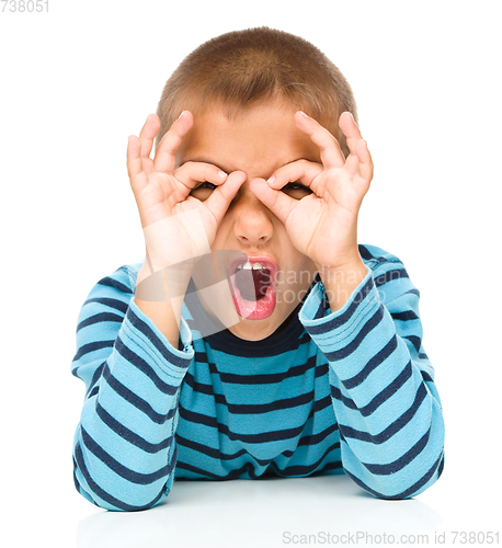 Image of Astonished little boy is showing glasses gesture