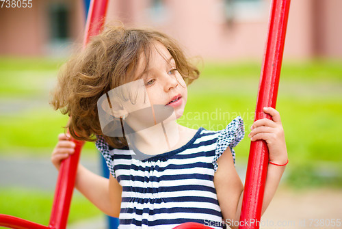 Image of Young happy girl is swinging in playground