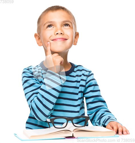 Image of Young boy is daydreaming while reading book