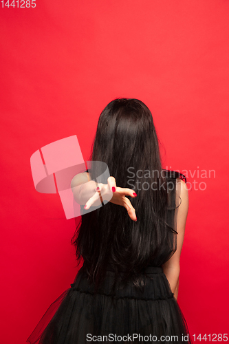 Image of Young woman in hat and dress as a witch on red background