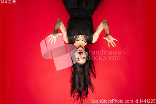 Image of Young woman in hat and dress as a witch on red background