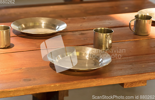 Image of Very old metal cups and plates on a wooden table